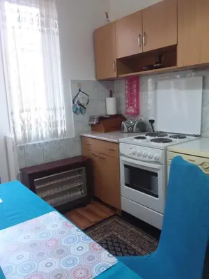 a kitchen with a stove and a table with a blue chair at Ikaria in Niš