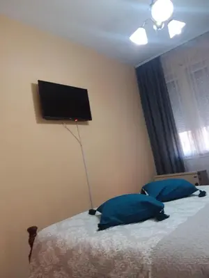 a bedroom with a bed with blue pillows and a flat screen tv at Ikaria in Niš
