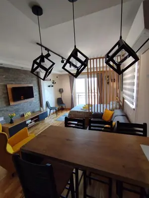 a living room with a table and a bedroom at Apartman Gold in Vrnjačka Banja