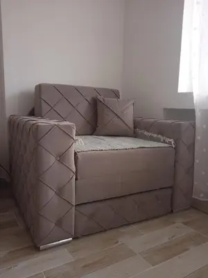 a brown couch sitting in a corner of a room at MAL Apartman in Soko Banja