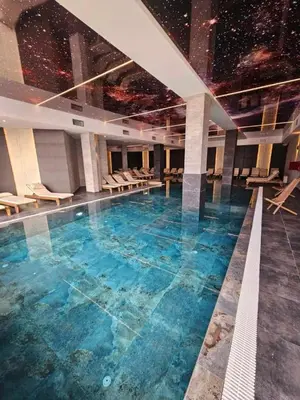 a large swimming pool with blue water in a building at M&Alux Kopaonik in Cajetina