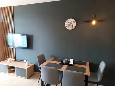 a dining room with a table and a clock on the wall at M&Alux Kopaonik in Cajetina
