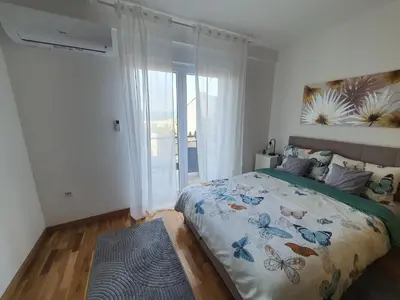 a bedroom with a bed and a large window at Apartman IRIS in Vrnjačka Banja