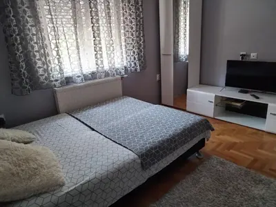 a small bedroom with a bed and a television at TEA APARTMAN in Niš