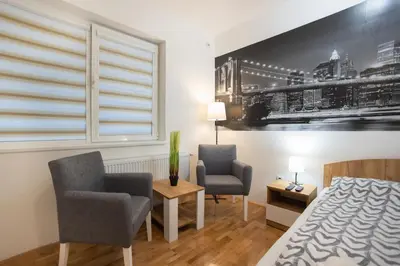a bedroom with two chairs and a bed and a window at V & V Studio Apartments 2 in Niš