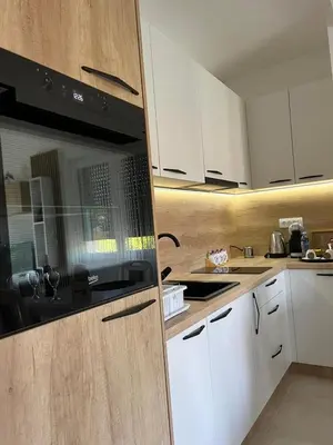 a kitchen with white cabinets and a black microwave at Apartman Gorsky in Vrnjačka Banja