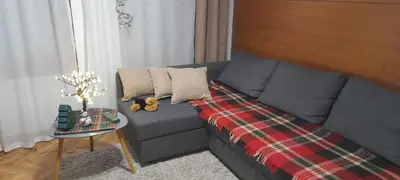 a living room with a gray couch with a plaid blanket at B&P apartman Vrnjačka Banja in Vrnjačka Banja