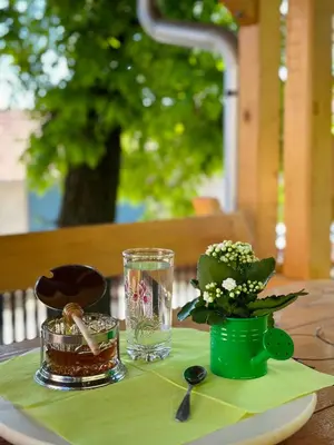 a table with a green plate with a vase of flowers at Seosko turističko domaćinstvo DUNJA in Osnić