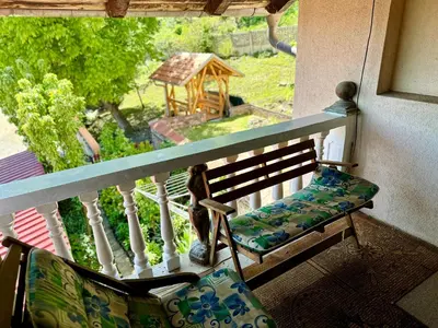 a bench on a balcony with a view of a garden at Seosko turističko domaćinstvo DUNJA in Osnić