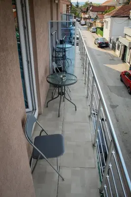 a balcony with a table and chairs on a street at Apartments and Rooms Radivojević Niš in Niš