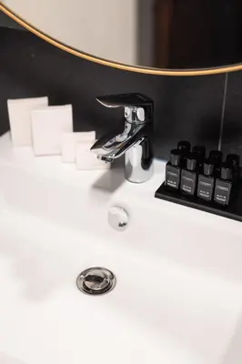a white bathroom sink with a round mirror on it at Hotel Kocka Vrnjačka Banja in Vrnjačka Banja