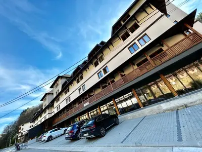 two cars parked in front of a building at Apartman Snezni Vrh - Bela Reka, Brzece in Brzeće