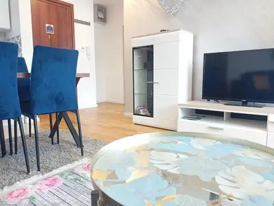 a living room with a glass table and blue chairs at OPERA LUX APARTMENTS Green Hill - Relax & Free Parking in Soko Banja