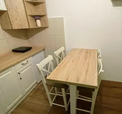 a kitchen with a wooden table and white chairs at Bela Reka Gondola Studio in Brzeće