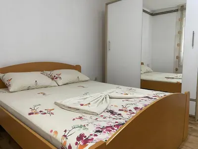 a bedroom with a bed with a floral blanket on it at Apartmani Dora Leskovac in Leskovac
