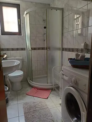 a bathroom with a shower and a washing machine at Apartmani Dora Leskovac in Leskovac