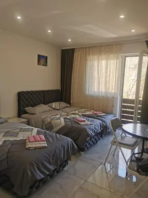three beds in a room with a table and chairs at Apartman Aleksandar 1 in Ribarska Banja