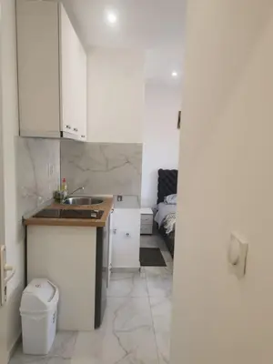 a kitchen with white cabinets and a sink and a bed at Apartman Aleksandar 1 in Ribarska Banja