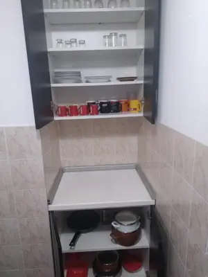 a small kitchen with a shelf with pots and pans at Apartman Kotin in Pirot