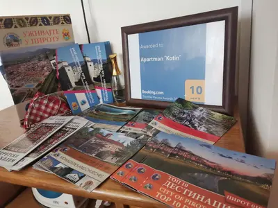 a desk with a computer monitor and a bunch of publications at Apartman Kotin in Pirot