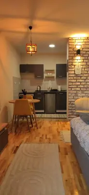 a living room with a table and a kitchen at Studio Iris 1 in Niš