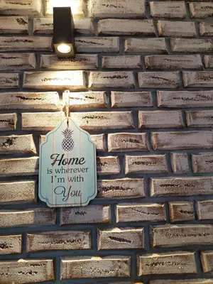 a sign that says home is whenever im with you on a brick wall at Studio Iris 1 in Niš