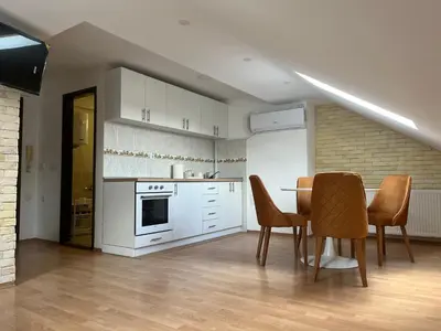 a kitchen with white cabinets and a table and chairs at Art Studio in Niš