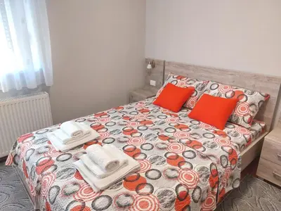 a bed with red pillows and towels on it at Apartman SN in Vrnjačka Banja