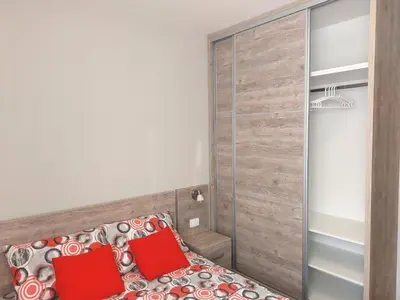 a bedroom with a bed with red pillows and a closet at Apartman SN in Vrnjačka Banja