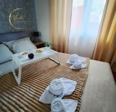 a room with a bed with a table and towels at Vlada apartmani in Vrnjačka Banja