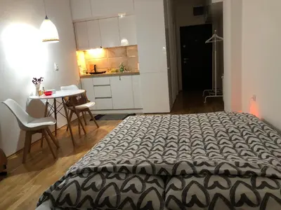 a bedroom with a bed and a table and a kitchen at Tesla 30 in Kruševac