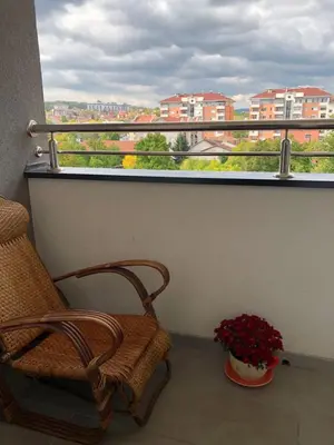 a balcony with a chair and a vase of flowers at Tesla 30 in Kruševac