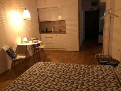 a bedroom with a bed and a table and a kitchen at Tesla 30 in Kruševac