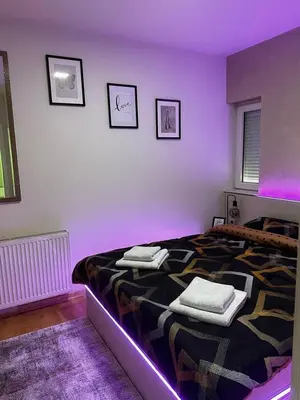 a purple bedroom with a bed with towels on it at L&D apartman in Kruševac