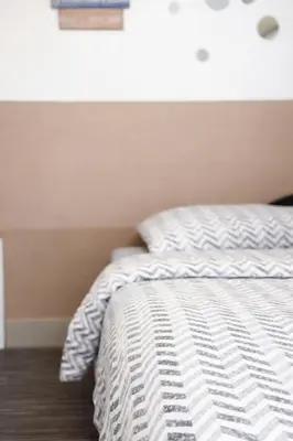 a bed with a white comforter in a bedroom at Nilton 2 Apartmans in Niš