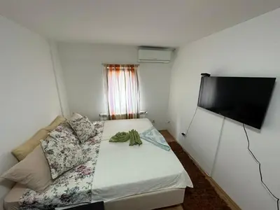 a small bedroom with a bed and a flat screen tv at Apartmani Ušće in Trstenik