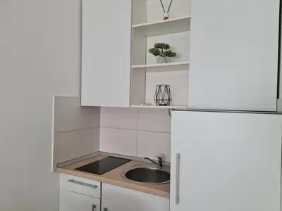 a kitchen with white cabinets and a sink at Babuska studio in Jagodina