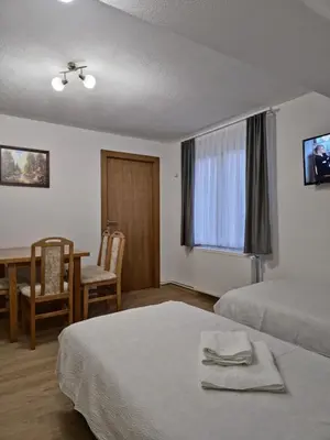 a hotel room with two beds and a table and chairs at Apartments Tatic in Kopaonik