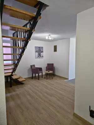 a room with a staircase and two chairs and a table at Apartments Tatic in Kopaonik