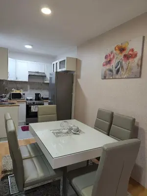 a white dining room table with chairs and a kitchen at Apartman LARA in Pirot