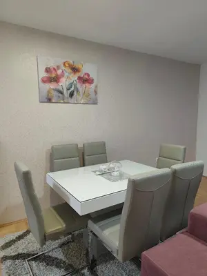 a dining room table with chairs and a painting on the wall at Apartman LARA in Pirot
