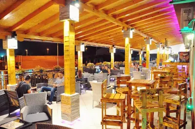 a restaurant with wooden tables and chairs and people sitting at Rooms Turist in Vladičin Han