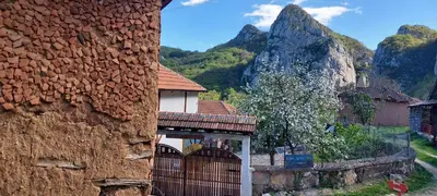 a building with a fence and mountains in the background at Golemi kamik Pirot Vlasi 4 in Pirot