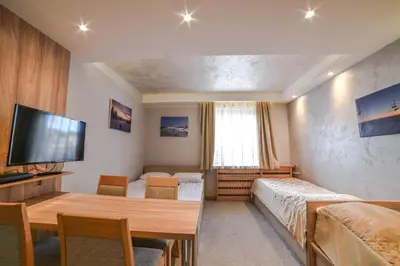 a room with two beds and a table and a television at Apartments Suncani Vrhovi Kopaonik in Kopaonik