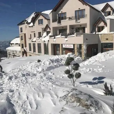 a building covered in snow with a small tree in it at Kopaonik - Milmari resort S65 in Kopaonik