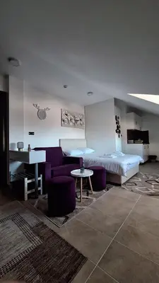 a bedroom with a bed and a table and purple chairs at Kopaonik - Milmari resort S65 in Kopaonik