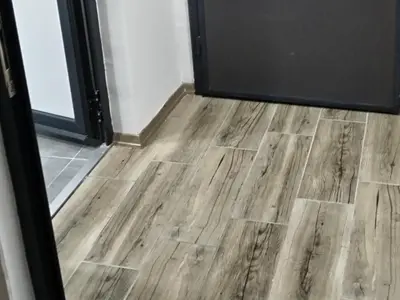 a room with a wooden floor in front of a door at Junona Magenta in Prokuplje