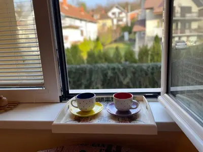 two coffee cups sitting on a tray in a window at Just like home in Vrnjačka Banja