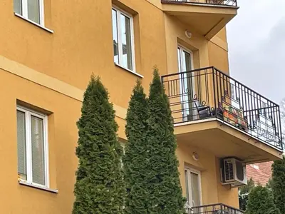 a building with a balcony and two trees in front of it at Just like home in Vrnjačka Banja
