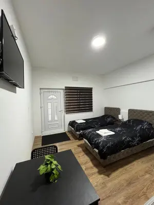 a room with two beds and a table and a tv at Apartmani Ćosić - Kuršumlijska banja in Kursumlijska Banja
